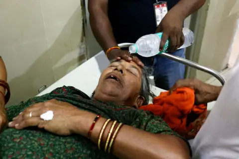 Niharika Kulkarni/AFP A hospital staff member pours water on the face of a patient suffering from heat stroke at a government hospital during a severe heatwave in Varanasi on May 30, 2024. 