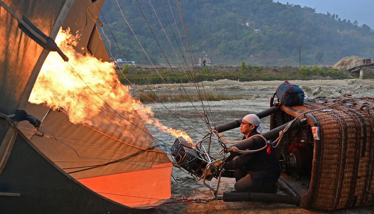 A participant prepares his hot air balloon during the international festival at Pokhara in Nepal on December 25, 2024. — AFP