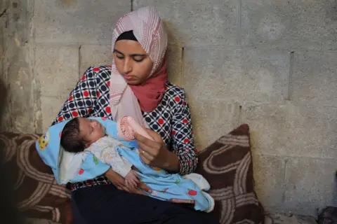 Hasan Jedi/Getty Images A Palestinian woman cools off her child while sleeping inside the tent at a refugee camp in Deir al-Balah, Gaza, on June 11, 2024.