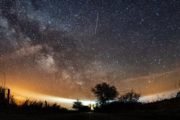 A setting sun, a night sky and a streaking meteor.